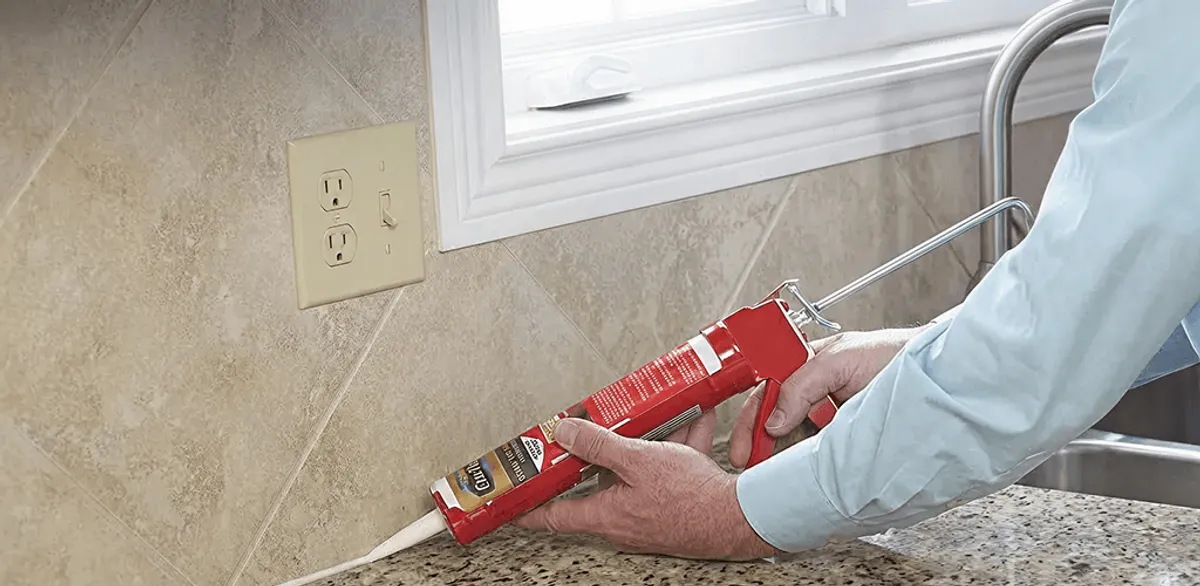 Handyman applying caulk along a kitchen backsplash and countertop seam in Richmond, VA